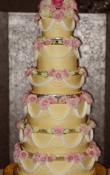 Gold buttercream iced, 5 tier Round wedding cake.  Fresh Flowers used as the topper. Some layers are Triple or quadruple to make varied thicknesses in the layers. 
(a cake plateau is used to direct your attention toward the cake and make it appear taller )